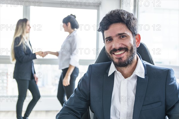 Portrait smiling businessman front women shaking hands