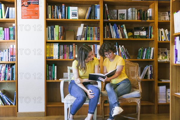 Teen friends reading book chairs