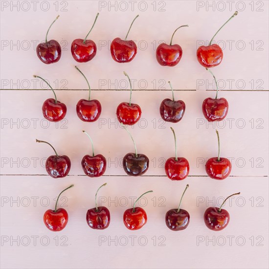 Row ripe juicy cherries pink wooden background