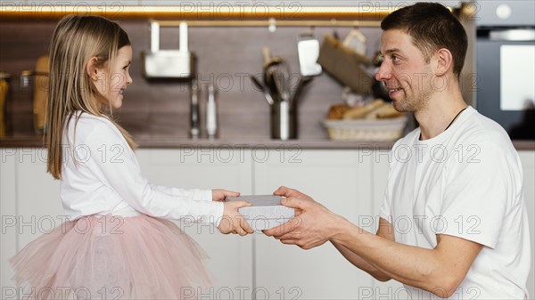 Side view smiley girl tutu skirt giving her dad present father s day