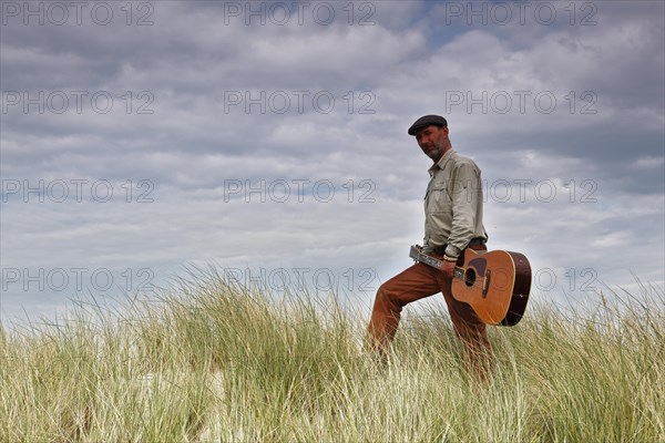 Man with guitar in the dunes