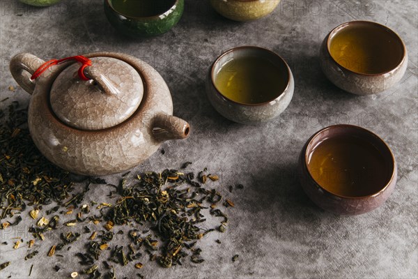 Chinese brown teapot teacups with tea herbs concrete backdrop