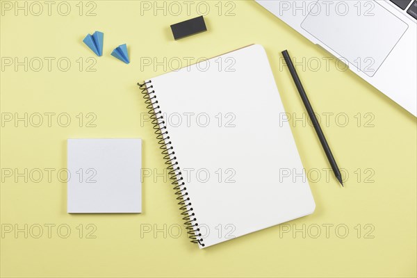 Laptop pencil spiral notebook adhesive notepad airplane eraser yellow background