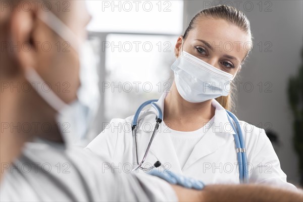 Female physiotherapist with medical mask examining man