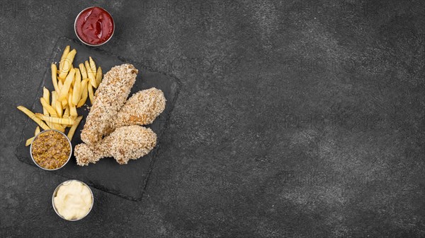 Flat lay fried chicken with french fries sauces