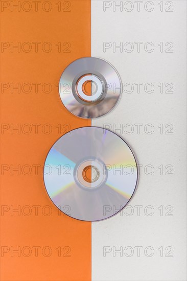 Overhead view compact discs orange white dual background