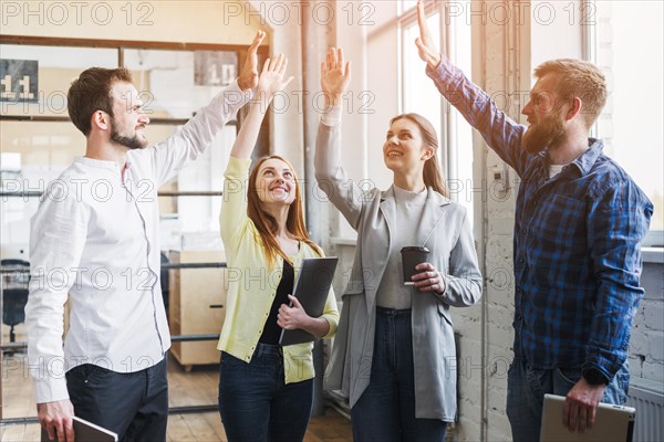 Young colleagues giving high five each other