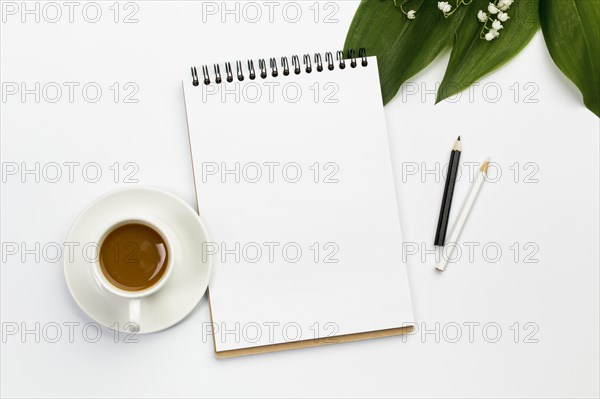 Coffee cup blank spiral notepad colored pencils with leaves flower office desk