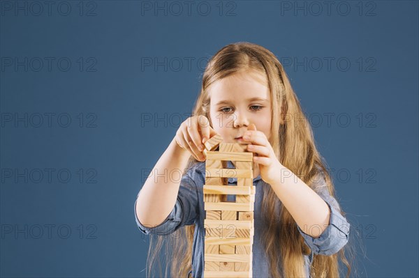 Focused girl building jenga tower