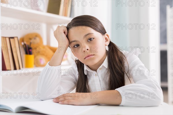 Tired schoolgirl doing homework desk