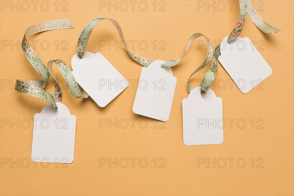 Designer ribbon through empty labels arranged bright yellow surface