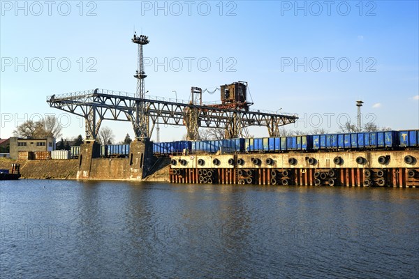 Old gantry crane in river port. Empty railway cars waiting for loading. Sunny day
