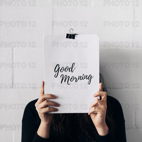 Close up female holding paper attach with paperclip good morning text front her face