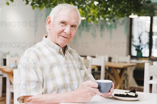 Elderly man drinking tea looking camera