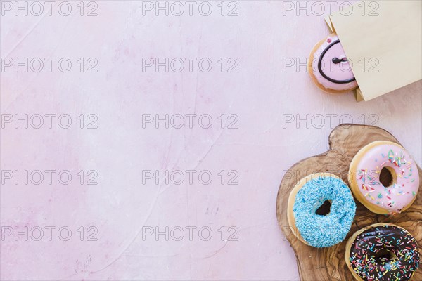 Fresh donuts chopping board near package pink background