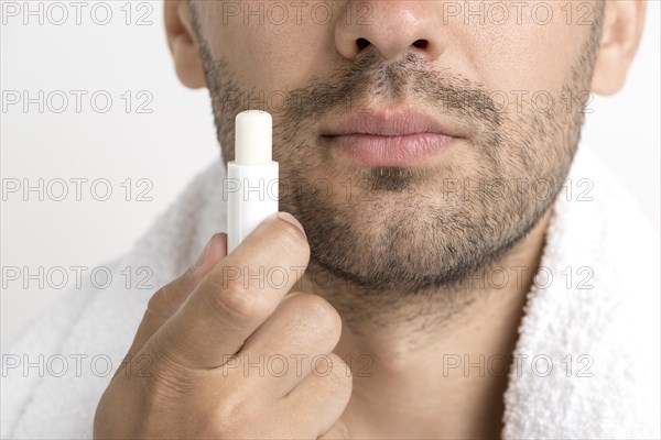 Lose up man with towel around his neck holding lip balm