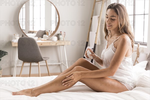 Woman sitting bed massaging her legs