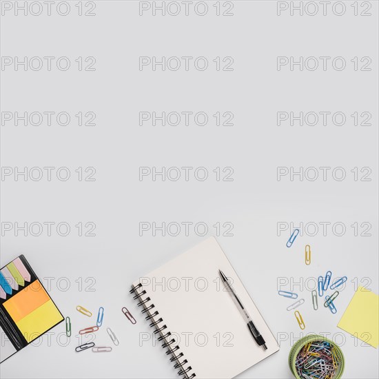 Colorful paper clips spiral notebook with pen adhesive notes white background