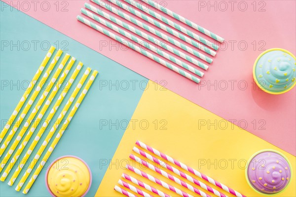 Colored surface with birthday cupcakes straws