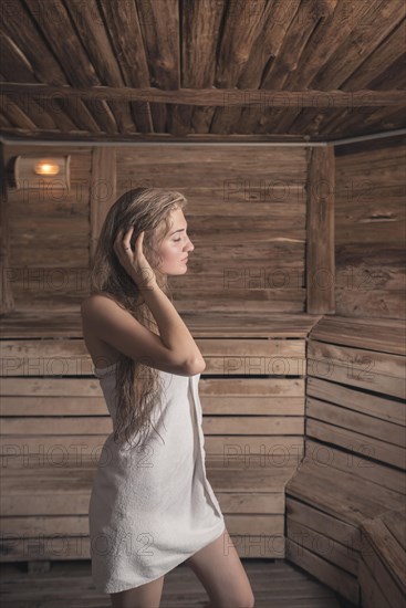Woman with wet long hair standing hot sauna