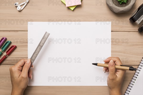 From hands holding ruler pen blank paper sheet