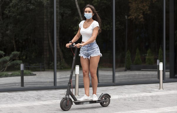 Woman with medical mask riding electric scooter