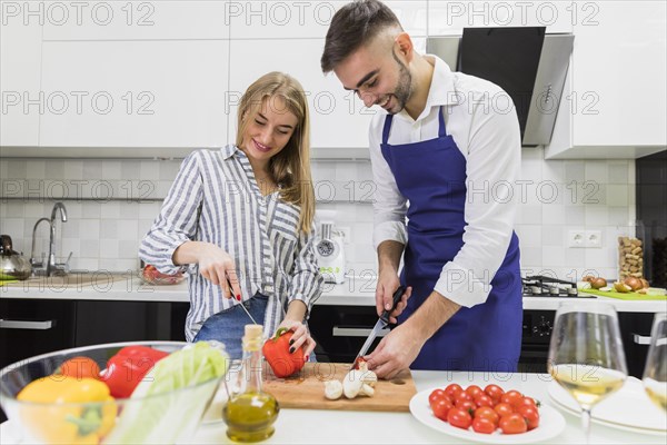 Couple cutting vegetables wooden board