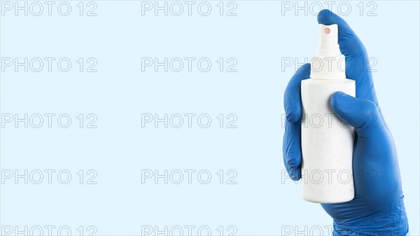 Hand with latex glove holding spray bottle with copy space