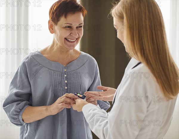 Smiley covid recovery center female doctor checking elder patient s oxygen level