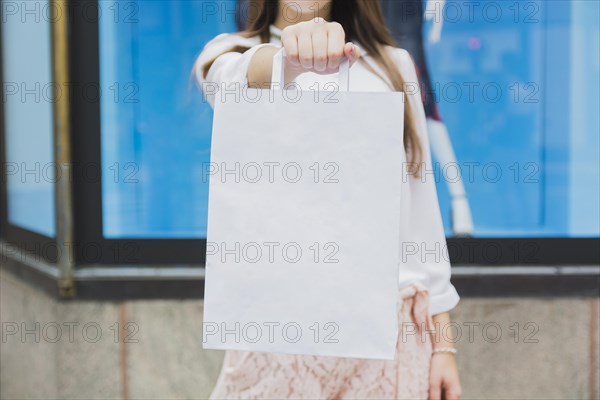 Woman holding shopping bag near shop window