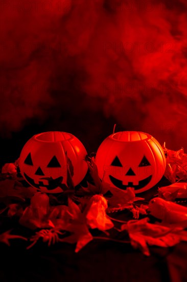 Halloween pumpkins on autumn leaves with smoke on a red background