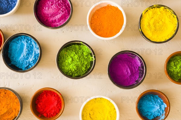 Elevated view holi color powder different type bowls concrete backdrop