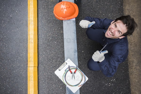 High angle view happy male electrician showing thumb up workplace