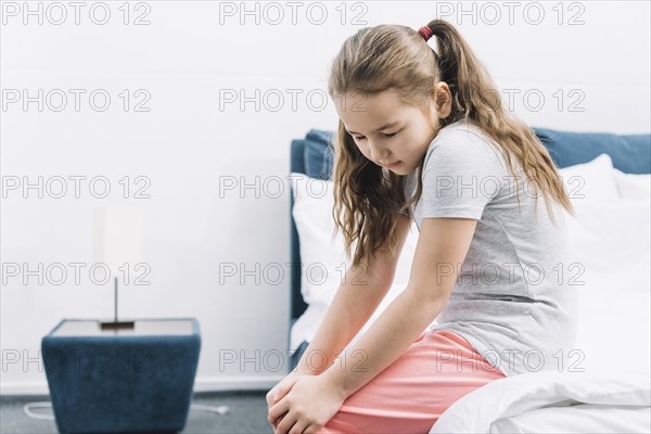 Close up girl sitting bed suffering from knee pain