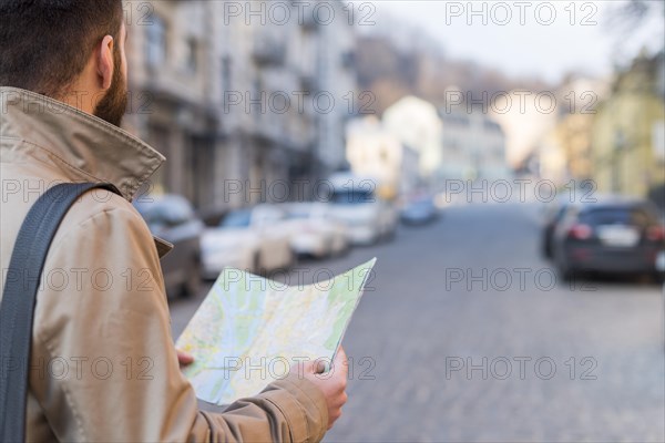 Male traveler holding map hand finding way city street