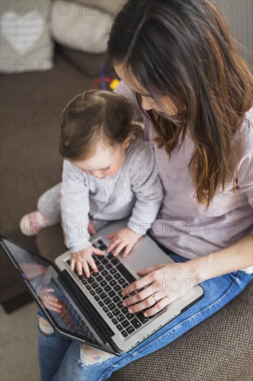 Overhead view mother sitting with her child using laptop