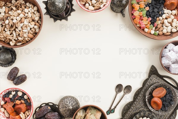 Dried fruits nuts dates lukum baklava metallic bowl white backdrop with space center