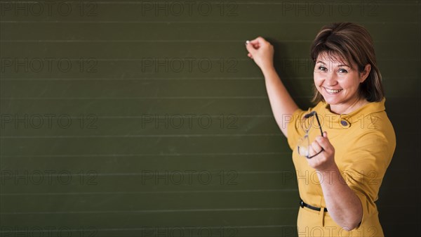 Teacher pointing chalkboard with copy space