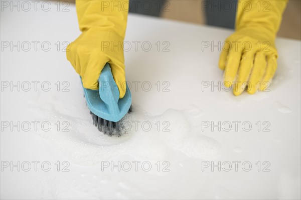High angle woman with cleaning gloves using brush