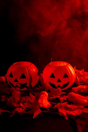 Halloween pumpkins on autumn leaves with smoke on a red background