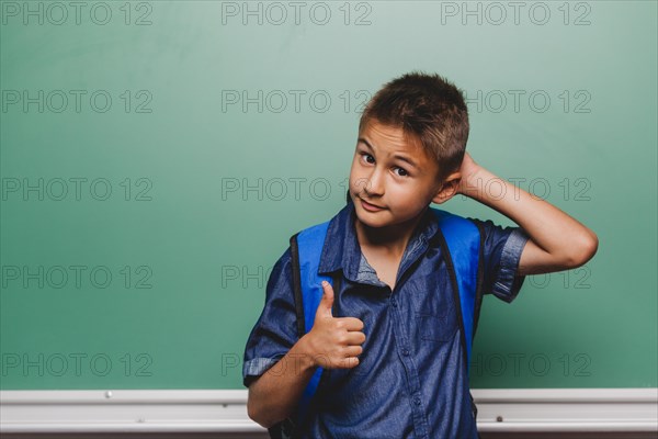 Boy scratching head gesturing thumb up