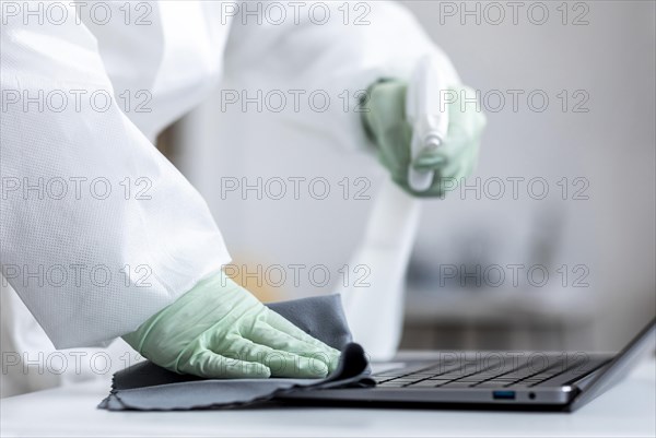 Person disinfecting dangerous area while wearing protective suit