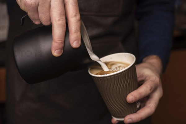 Close up person pouring milk into coffee cup