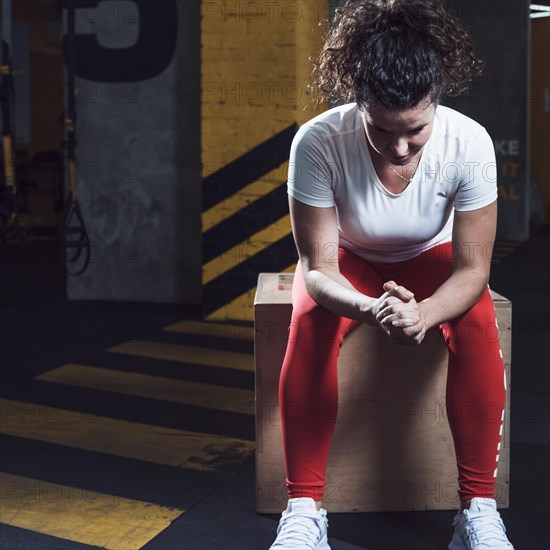 Fit woman sitting wooden box gym