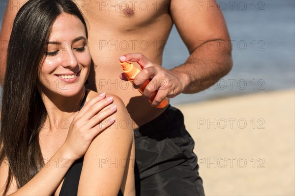 Man helping woman apply sunscreen beach