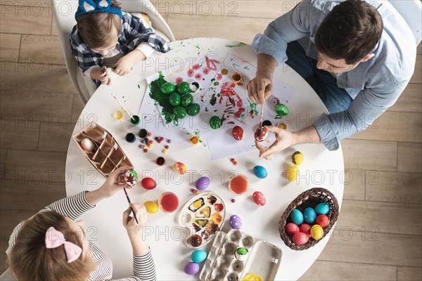 Top view family painting easter eggs together