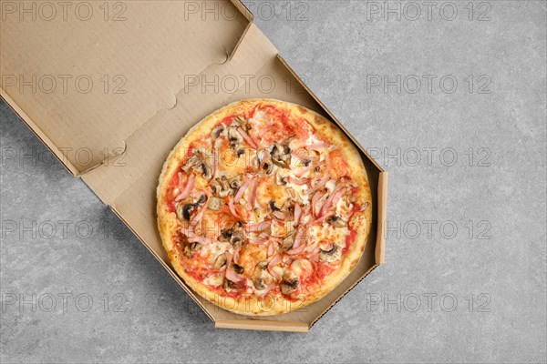Pizza with ham and champignon mushrooms in cardboard box