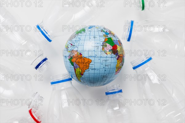 Earth globe surrounded plastic bottles grey table