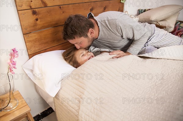 Father kissing his daughter s forehead before going sleep