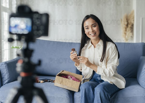 Woman live streaming home with make up tools